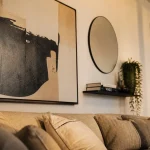 Décorer un mur avec cadres, miroir et reliefs pour réchauffer le salon